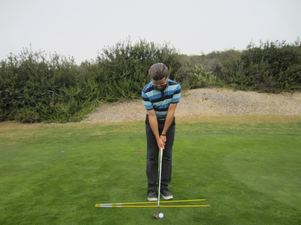 Note the open stance, square club face, and head position forward of the golf ball.